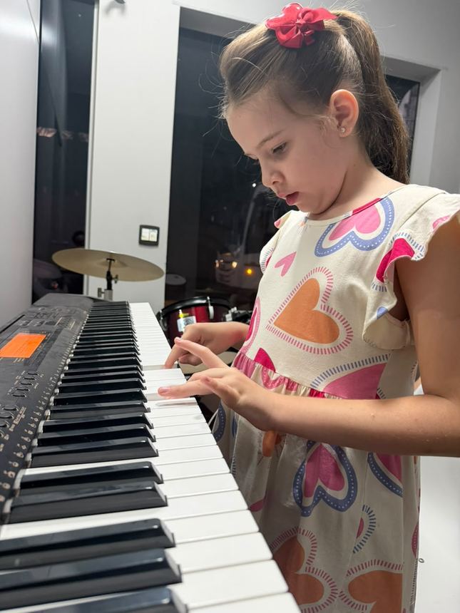 Menina pequena tocando teclado na sala da escola